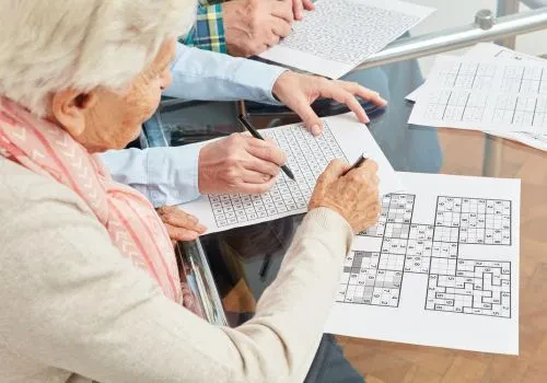 An elderly couple doing crossword and sudoku puzzles