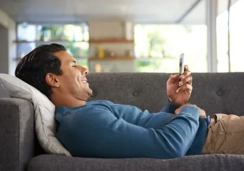 A man happy while playing a mobile game alone