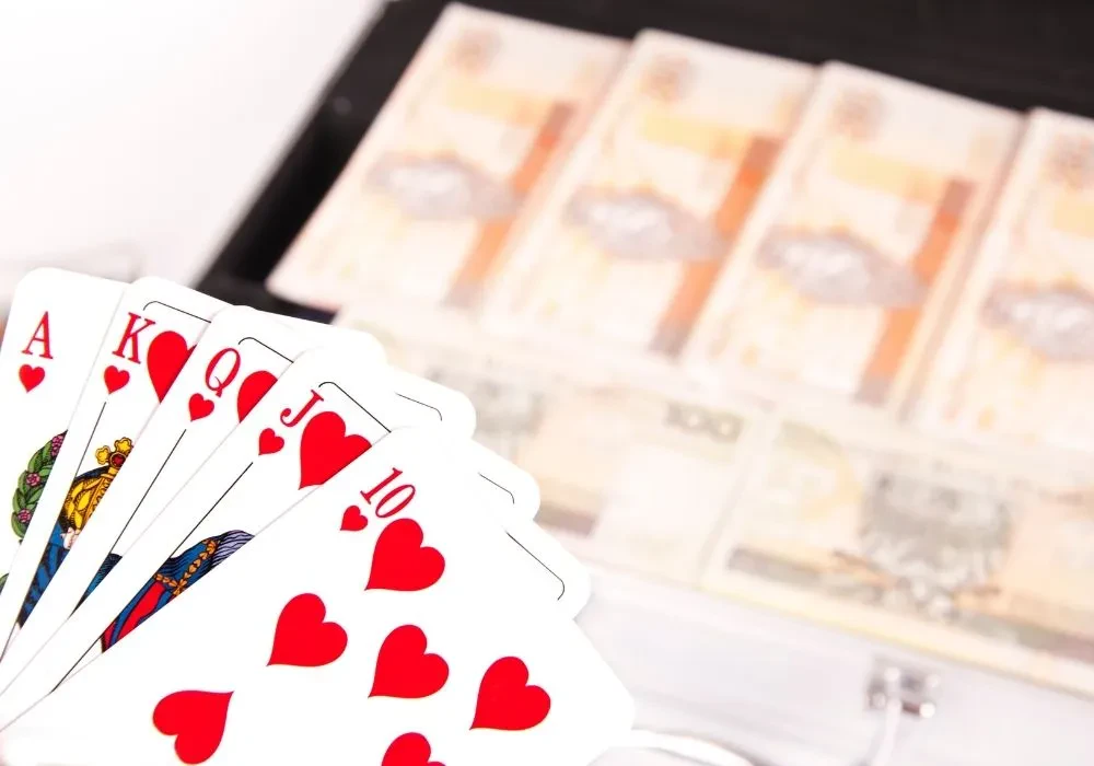 Playing cards in the foreground with lots of money in the blurred background